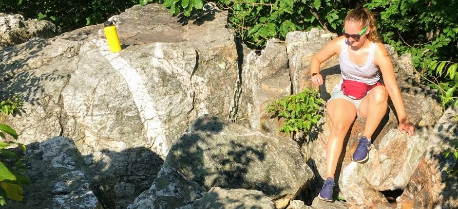 girl sitting on top of big gray rock