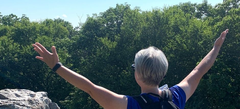 lady holding out hands at trees and sky